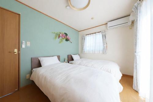 two beds sitting next to each other in a bedroom at Beppu Paw House in Beppu