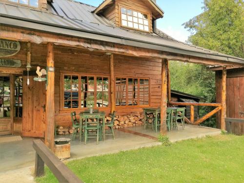 a wooden cabin with chairs and a table on a porch at Hotel El Barranco in Futaleufú