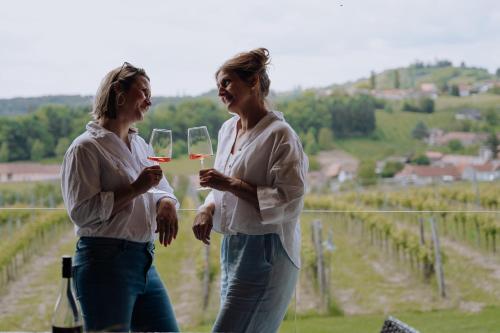 two women drinking wine in front of a vineyard at Winzerhof - Deutsch Haseldorf in Deutsch Haseldorf