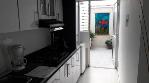 una cocina con armarios blancos y una ventana con una pintura en La Estación, en Dosquebradas