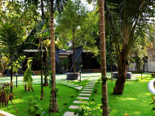 a garden with palm trees and a building at Creek Cottage in Kollam