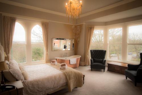 a bedroom with a bed and a chair and windows at Brockley Hall Hotel in Saltburn-by-the-Sea