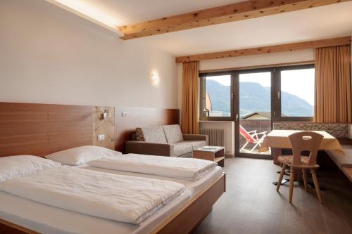 a bedroom with two beds and a desk and a chair at Hotel Appartement Inge in Tirolo