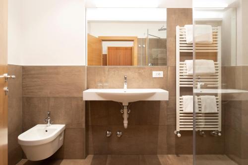 a bathroom with a sink and a mirror and a toilet at Hotel Appartement Inge in Tirolo