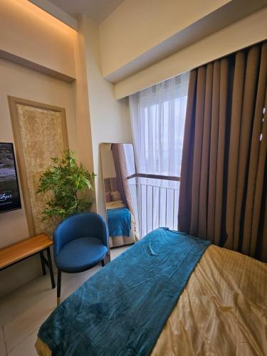 a bedroom with a bed and a window and a chair at Alder Wind Staycations Tagaytay in Kaybagal
