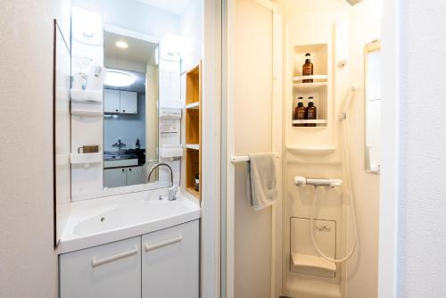 a white bathroom with a sink and a mirror at 第2舞鶴ハイツ in Fukuoka