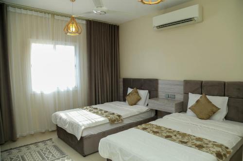 a hotel room with two beds and a window at Al Sahwa Residency in Ţāqah
