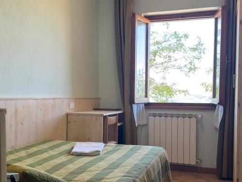 a bedroom with a bed and a large window at Hotel Da Giovanna in Chiusi della Verna