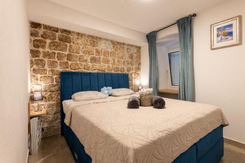 a bedroom with a blue bed with two stuffed animals on it at Apartmani Žunić in Pag