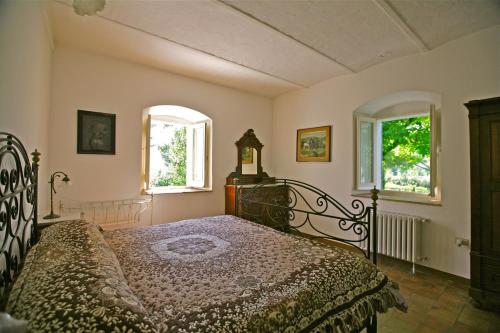 a bedroom with a bed and two windows at Agriturismo "Borgo Madonna degli Angeli" - charming cottages in the gardens ! in Tocco da Casauria