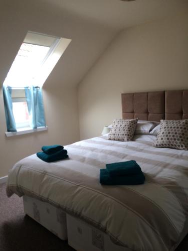 a bedroom with a large bed with two blue towels on it at The Old Coach House in Eyemouth