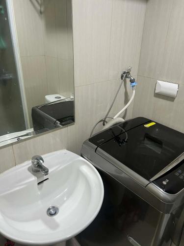 a bathroom with a white sink and a mirror at Shell Residences in Sampong