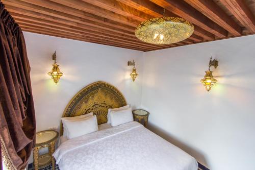 a bedroom with a bed and a chandelier at Riad Dar Bab Guissa in Fès