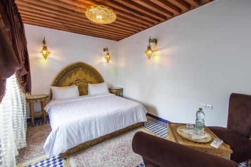 a bedroom with a bed and a table and a chair at Riad Dar Bab Guissa in Fès