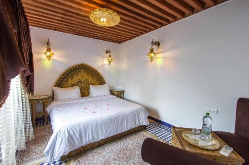 a bedroom with a bed and a table and a couch at Riad Dar Bab Guissa in Fès