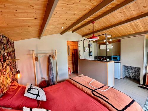 a bedroom with a large red bed and a kitchen at Cabane romantique climatisée avec piscine en pleine nature in Montignac