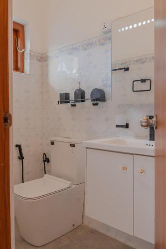 a white bathroom with a toilet and a sink at Boutique Dinu in Kandy