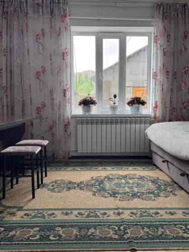 a bedroom with a bed and a window with flowers at Sun Garden Guest House in Ak-Say