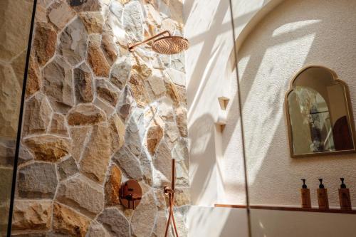 a shower in a bathroom with a stone wall at Miliyana Boutique Hotel - Adults Only in Kuta Lombok