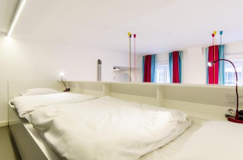 two white beds in a room with windows at Sara's Apartment in Budapest