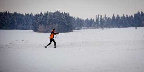 a man walking across a snow covered field at Penzión Ľadoveň SKVELÁ KUCHYŇA A RODINNÁ ATMOSFÉRA in Martin