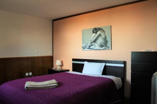 - une chambre dotée d'un lit violet avec une photo sur le mur dans l'établissement Alojamento Rural de Sendim da Serra, à Sendim da Serra