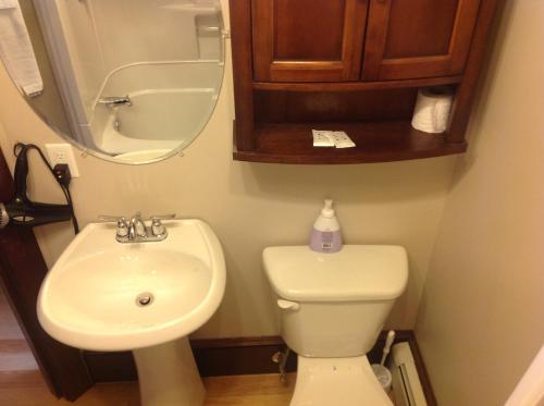 een badkamer met een wastafel, een toilet en een spiegel bij Maison McKenzie House in Campbellton
