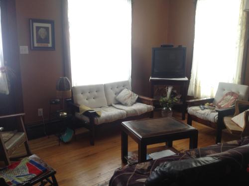 a living room with a couch and a tv at Maison McKenzie House in Campbellton
