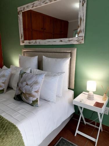 a bed with white pillows and a table with a lamp at 47atKabega in Gqeberha