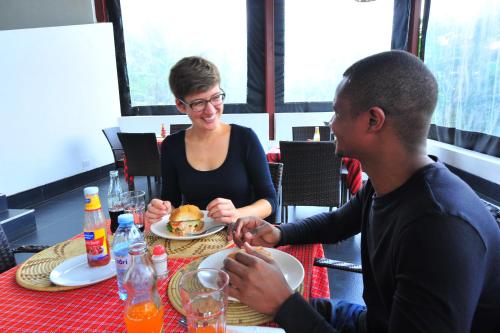a man and a woman sitting at a table eating food at Koi Koi, Fort Portal in Fort Portal