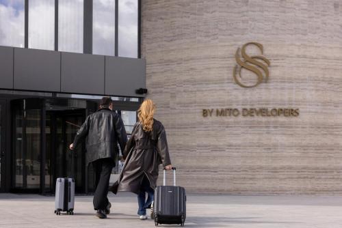 a man and woman walking past a building with luggage at Serbellas Boutique Hotel in Paphos