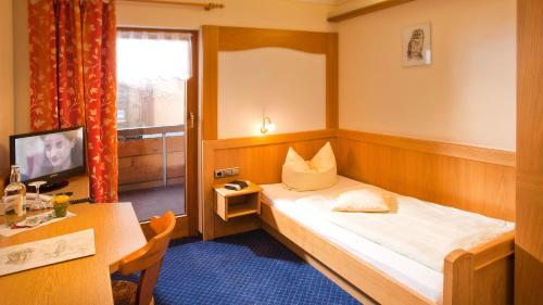 a small room with a bed and a desk and a television at Hotel Gasthof Rose in Oy-Mittelberg