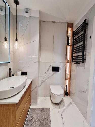 a white bathroom with a sink and a toilet at Apartament Ryżowa 66B in Warsaw