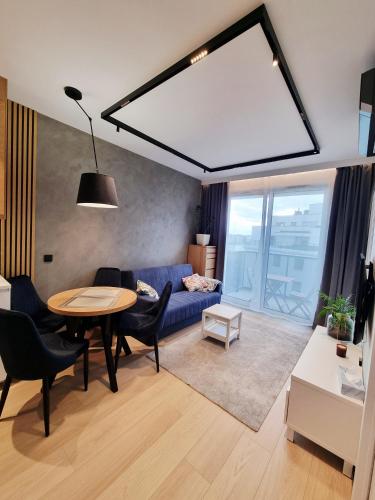 a living room with a blue couch and a table at Apartament Ryżowa 66B in Warsaw