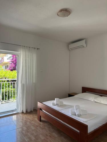 a white bedroom with a bed and a balcony at Hugo in Promajna