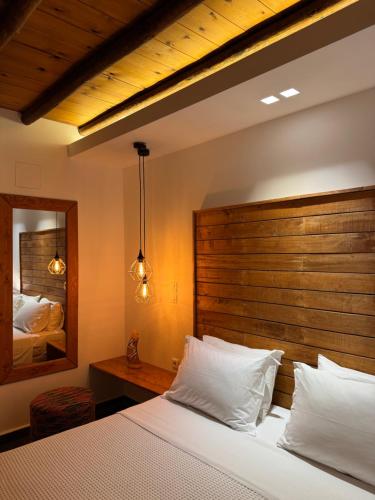 a bedroom with a bed with a wooden headboard and a mirror at PANORAMIO in Batsi