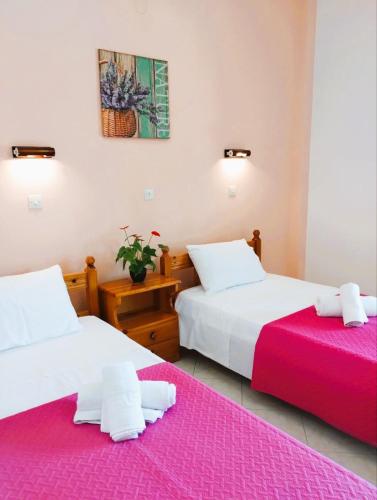 two beds in a hotel room with pink sheets at Nikos Apartments 2 in Kavos