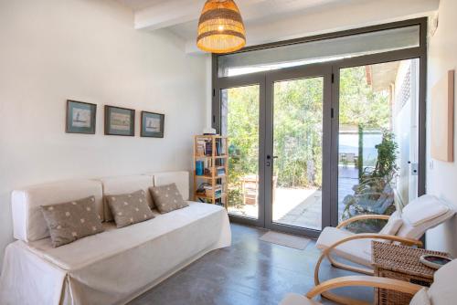 a living room with a white couch and a glass door at Villa Isabelle on the beach in Paralía Iríon