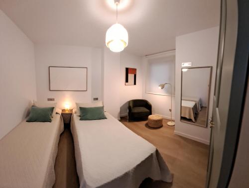 a room with two beds and a lamp and a mirror at Costa Canido II in Malpica