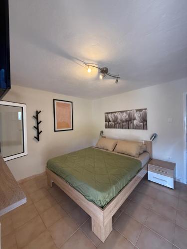 a bedroom with a bed with a green comforter at The Garden Studio AVLI Upper Vrasna in Nea Vrasna
