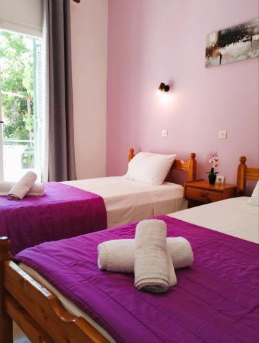 two beds in a room with purple sheets at Nikos Apartments 3 in Kavos