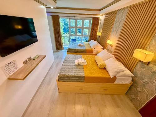 two beds in a room with a flat screen tv at S&L Lodging House and Tampisaw Restaurant in Pandan