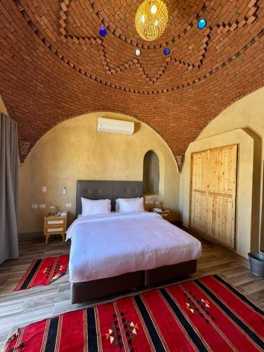 a bedroom with a large bed and a brick wall at Kom El Dikka Agri Lodge in ‘Izbat an Nāmūs