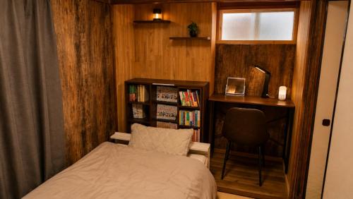 a bedroom with a bed and a chair and a book shelf at ペットok 古民家ふるさと真鶴 in Manazuru