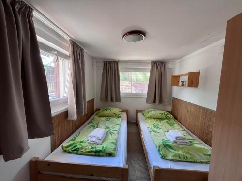 two beds in a room with two windows at Keszeg house in Szigetbecse