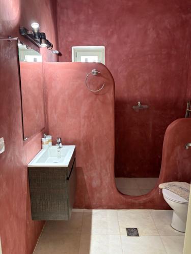 a red bathroom with a sink and a mirror at White House with Sea View in Ambelas