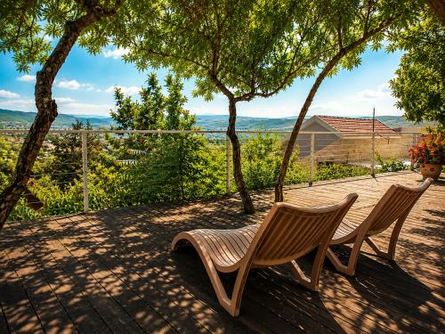 two wooden chairs sitting on a patio with a view at היחידה - Hayehida in Ma'alot Tarshiha