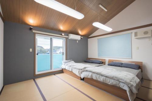 two beds in a room with a large window at umiakari in Naruto