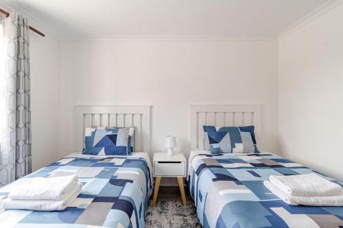 two beds in a bedroom with blue and white at Sintha guest house in Kraaifontein