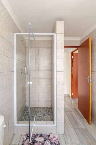 a shower with a glass door in a bathroom at Sintha guest house in Kraaifontein